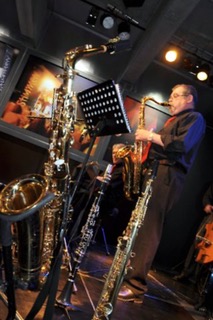 Saxofonist umgeben von mehreren Saxofonen auf der Bühne