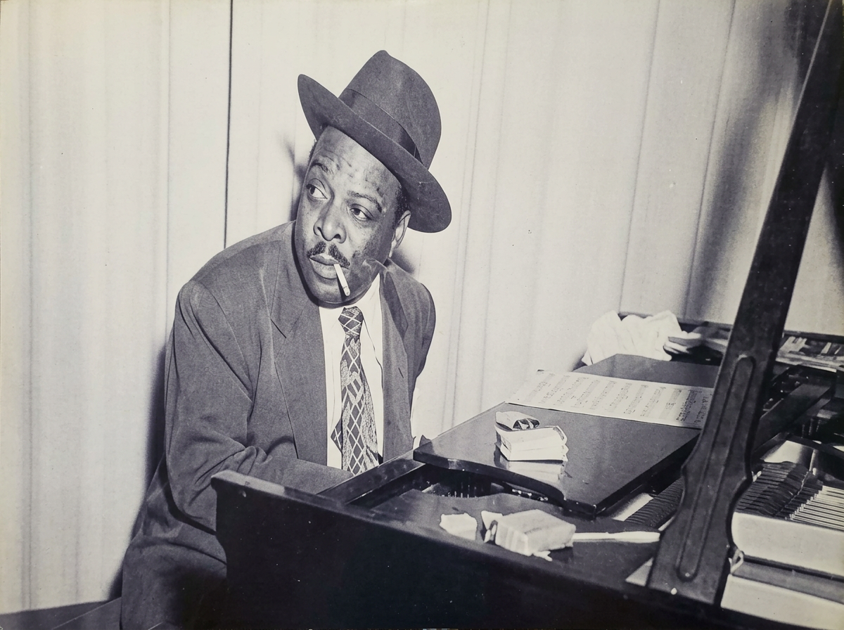 Historisches Schwarz-Weiß-Foto: Pianist mit Hut am Flügel